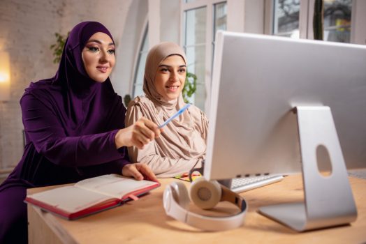happy-two-muslim-women-home-during-lesson-studying-near-computer-online-education